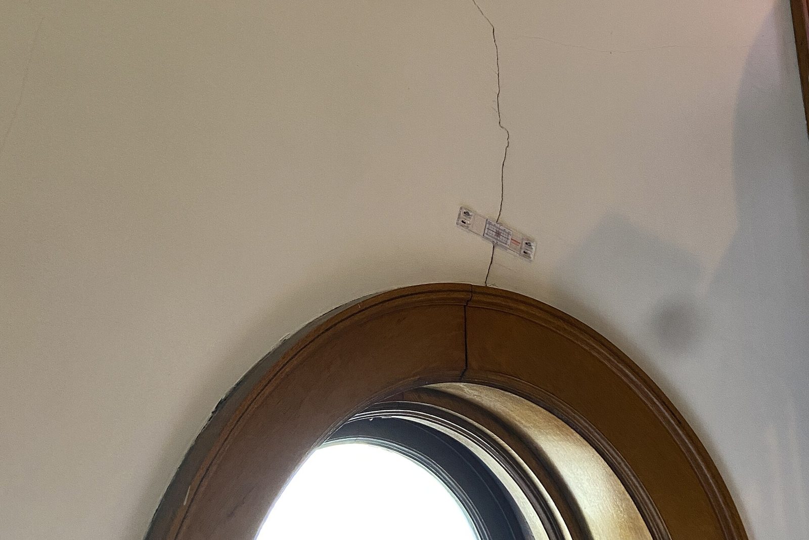 Rissmonitor auf einer Wand, der einen Riss oberhalb eines Fensterbogens überbrückt